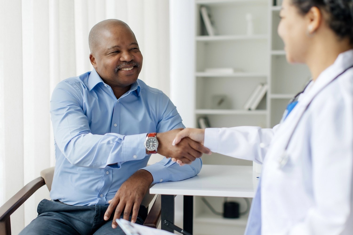 Doctor-Woman-And-Black-Male-Patient-Handshaking-During-Meeting-In-Clinic